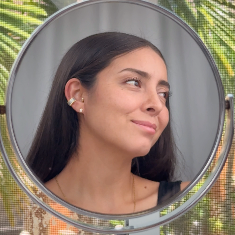 Woman looking into a round mirror with a blurred outdoor background