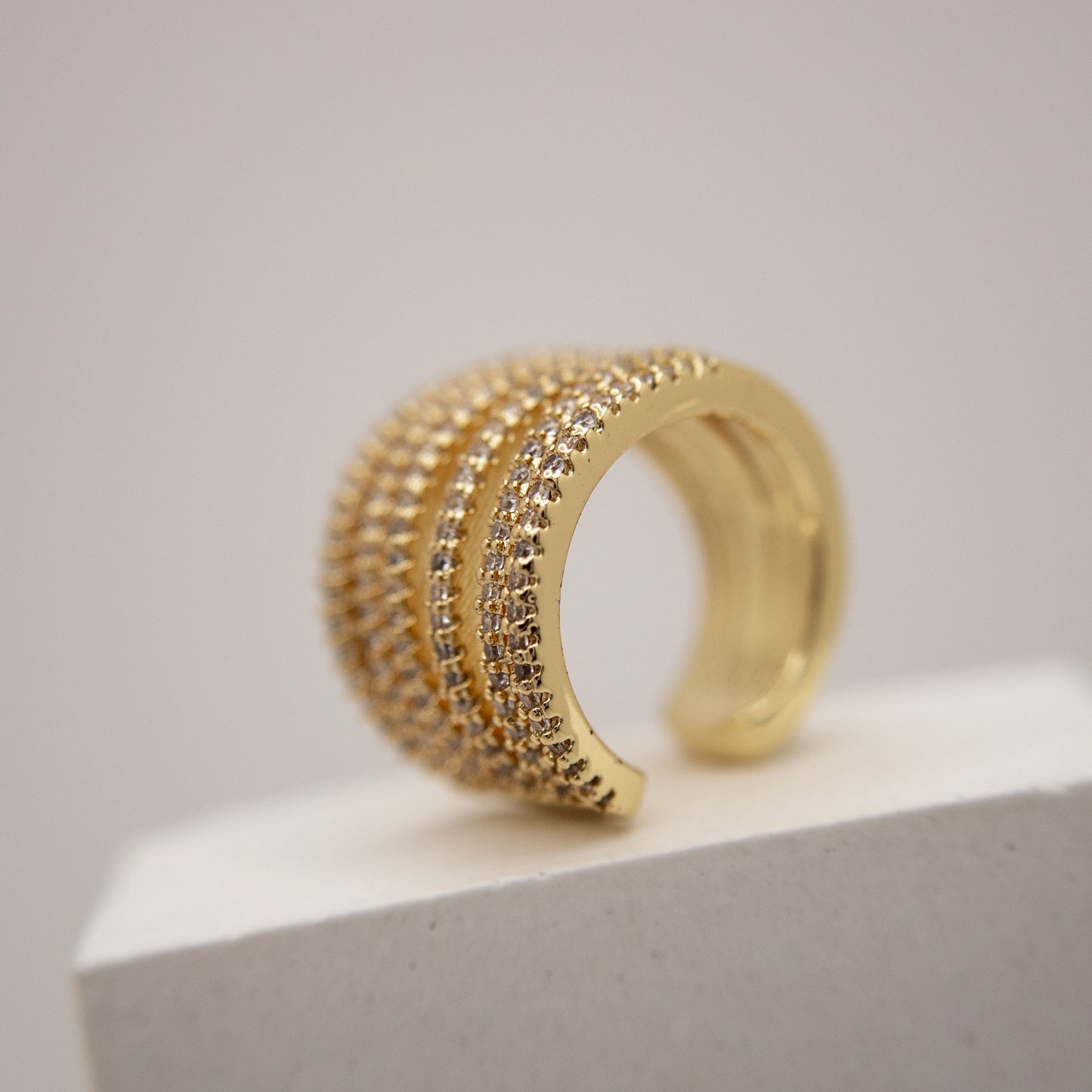 Gold ear cuff with multiple rows of diamonds on a light gray background