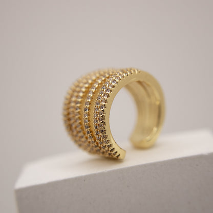 Gold ear cuff with multiple rows of diamonds on a light gray background