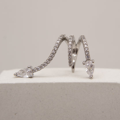 Pair of silver hoop ear cuff with clear gemstones on a light gray background