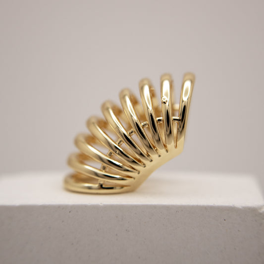 Gold ear cuff with a unique design on a light gray background