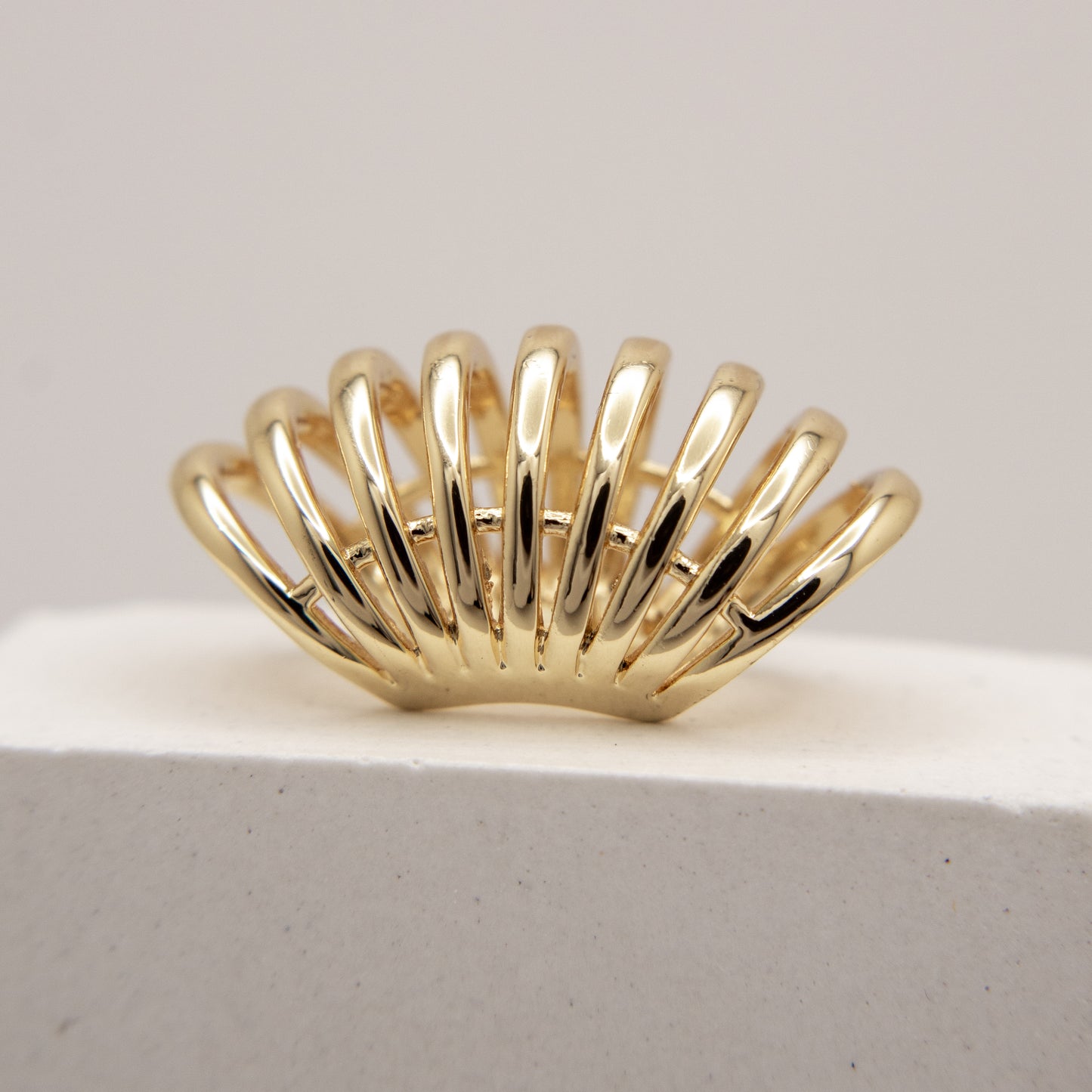 Gold ear cuff  with a unique design on a light gray background