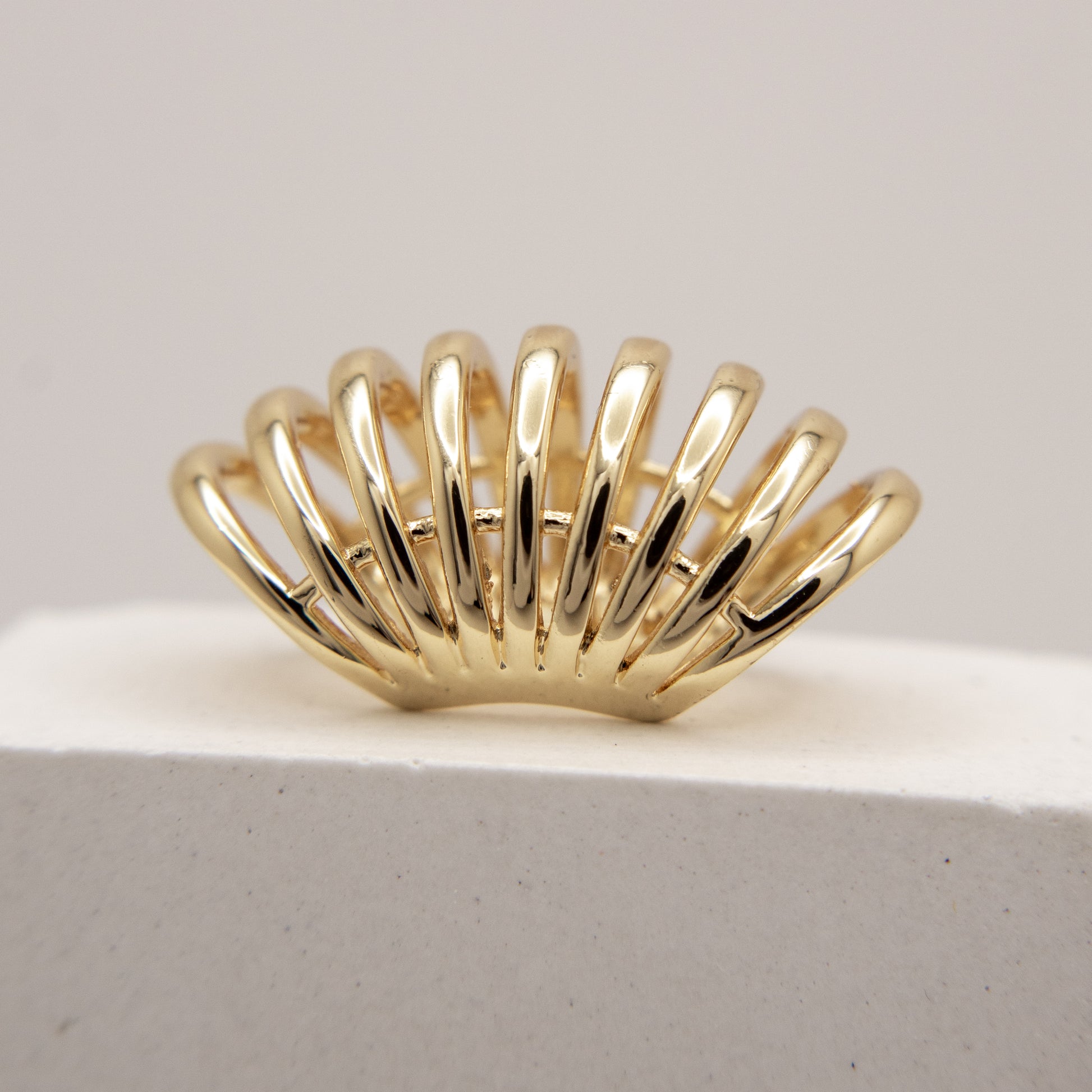 Gold ear cuff  with a unique design on a light gray background