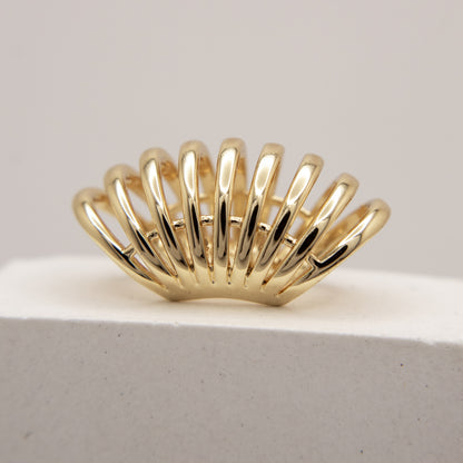 Gold ear cuff  with a unique design on a light gray background