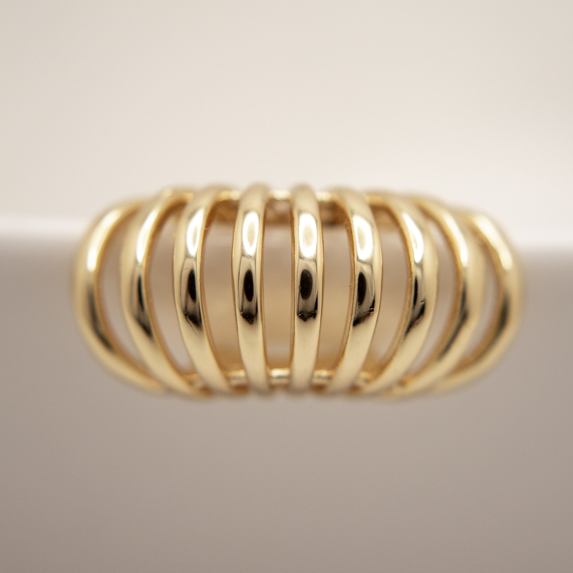 Gold ear cuff with a ribbed design on a light background