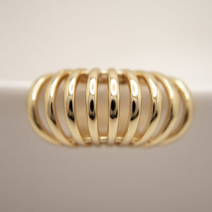 Gold ear cuff with a ribbed design on a light background