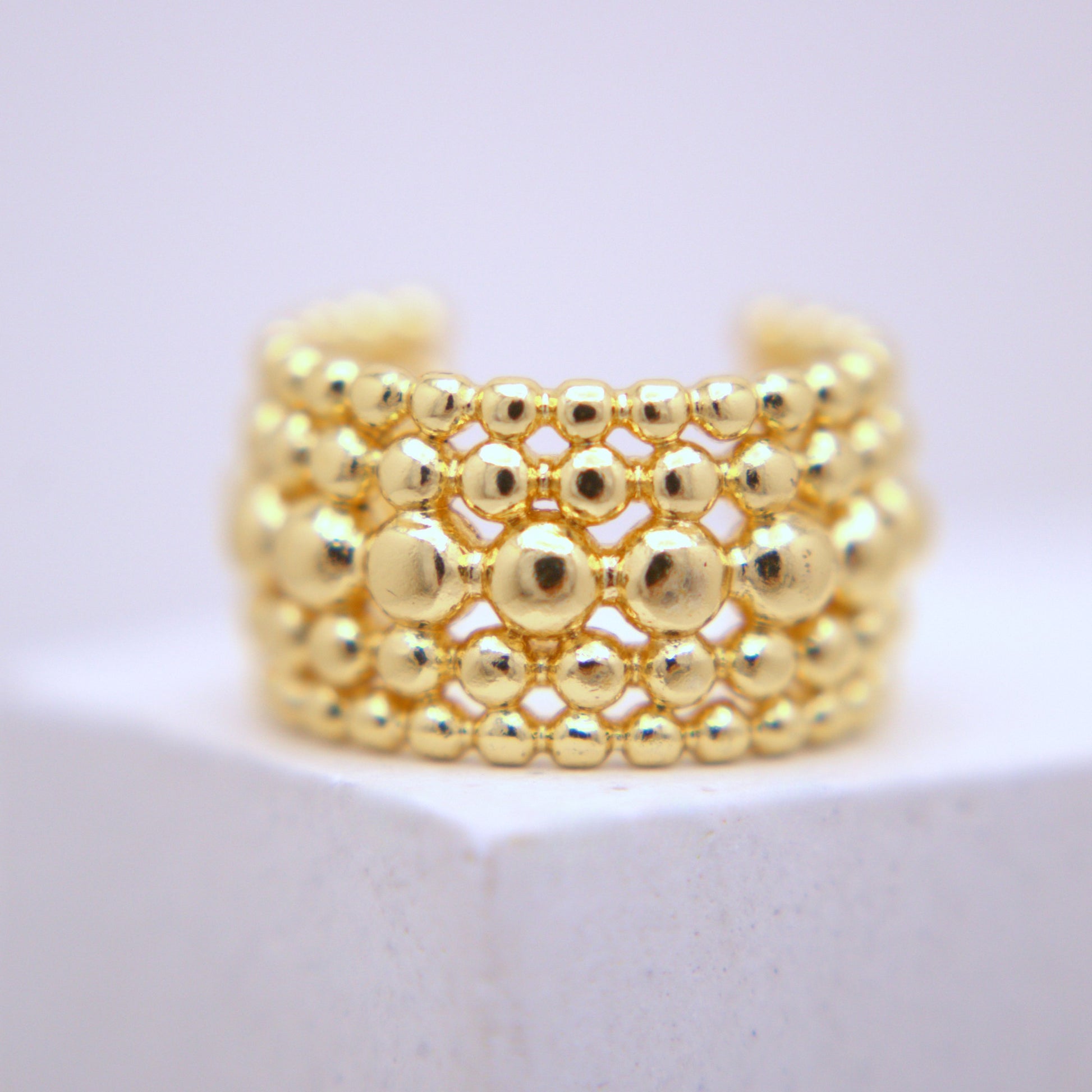 Gold beaded ear cuff on a white background