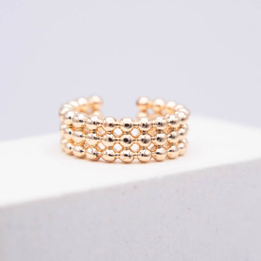 A rose gold beaded ring with three rows of small metallic beads, displayed on a white block against a light gray background.