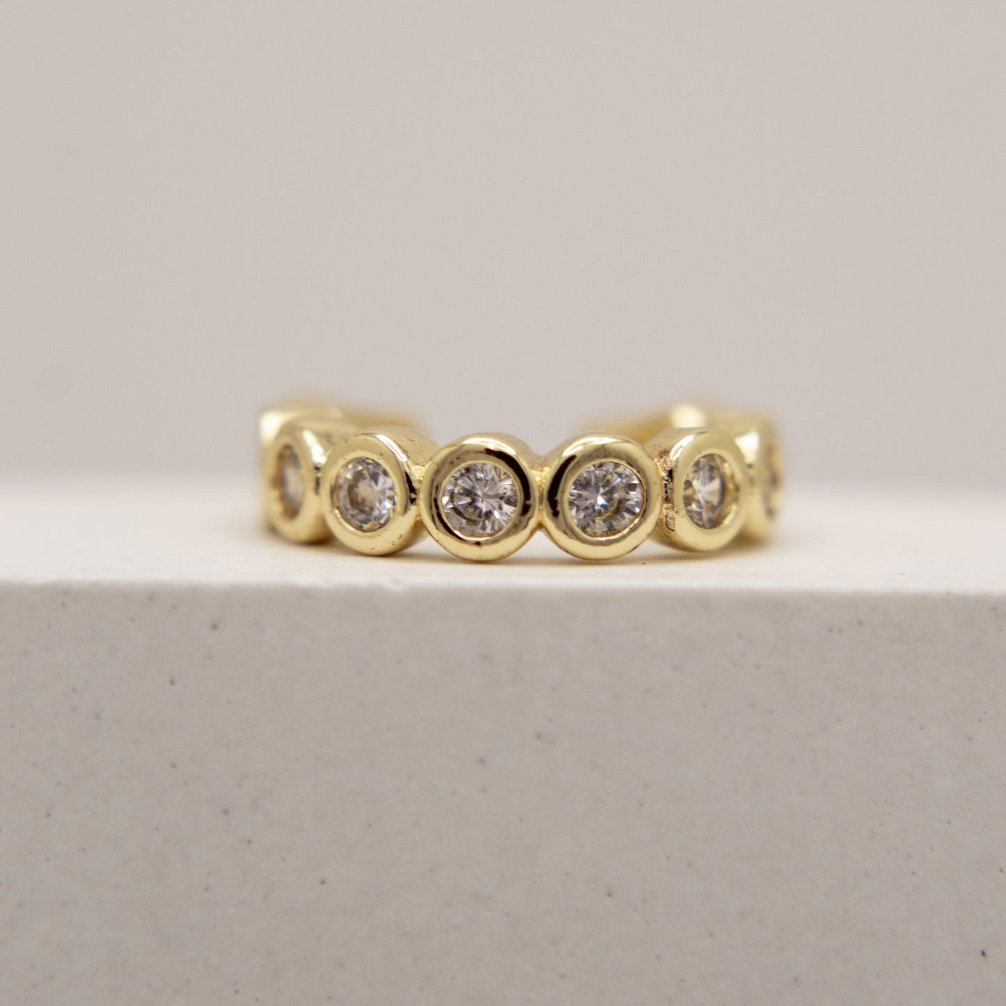 Gold ear cuff with embedded diamonds on a light gray background