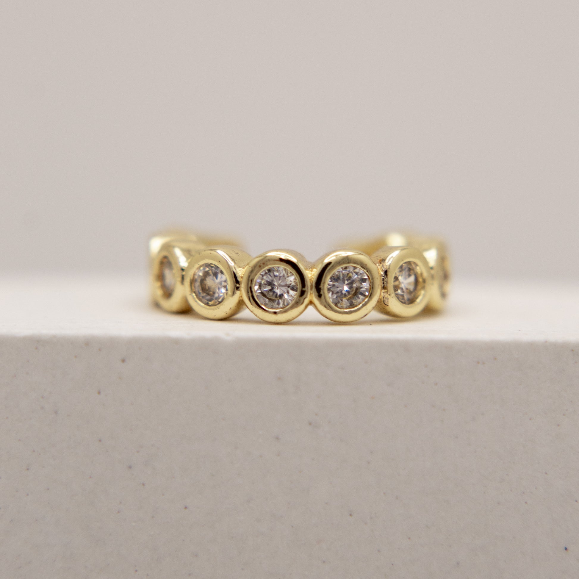 Gold ear cuff with embedded diamonds on a light gray background