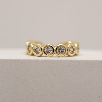 Gold ear cuff with embedded diamonds on a light gray background