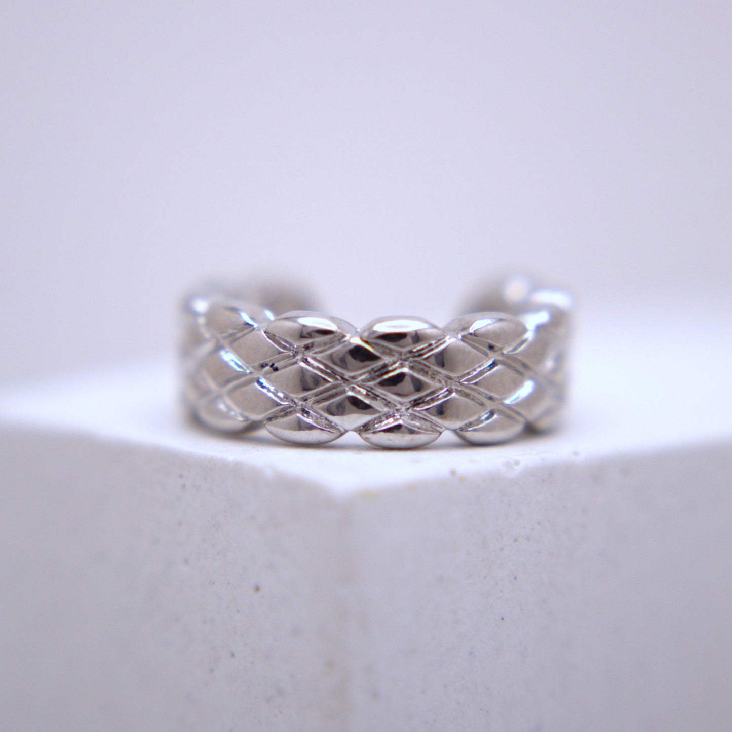 Silver woven ear cuff on a light gray background