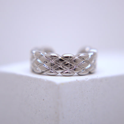 Silver woven ear cuff on a light gray background