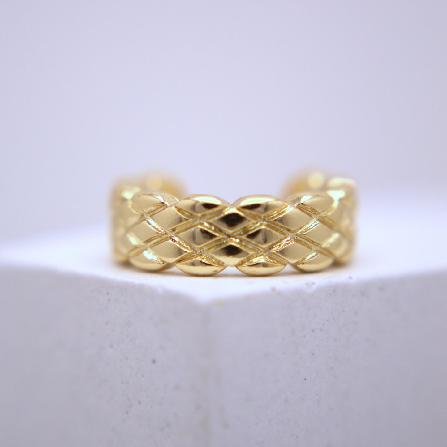 Gold woven ear cuff on a white background