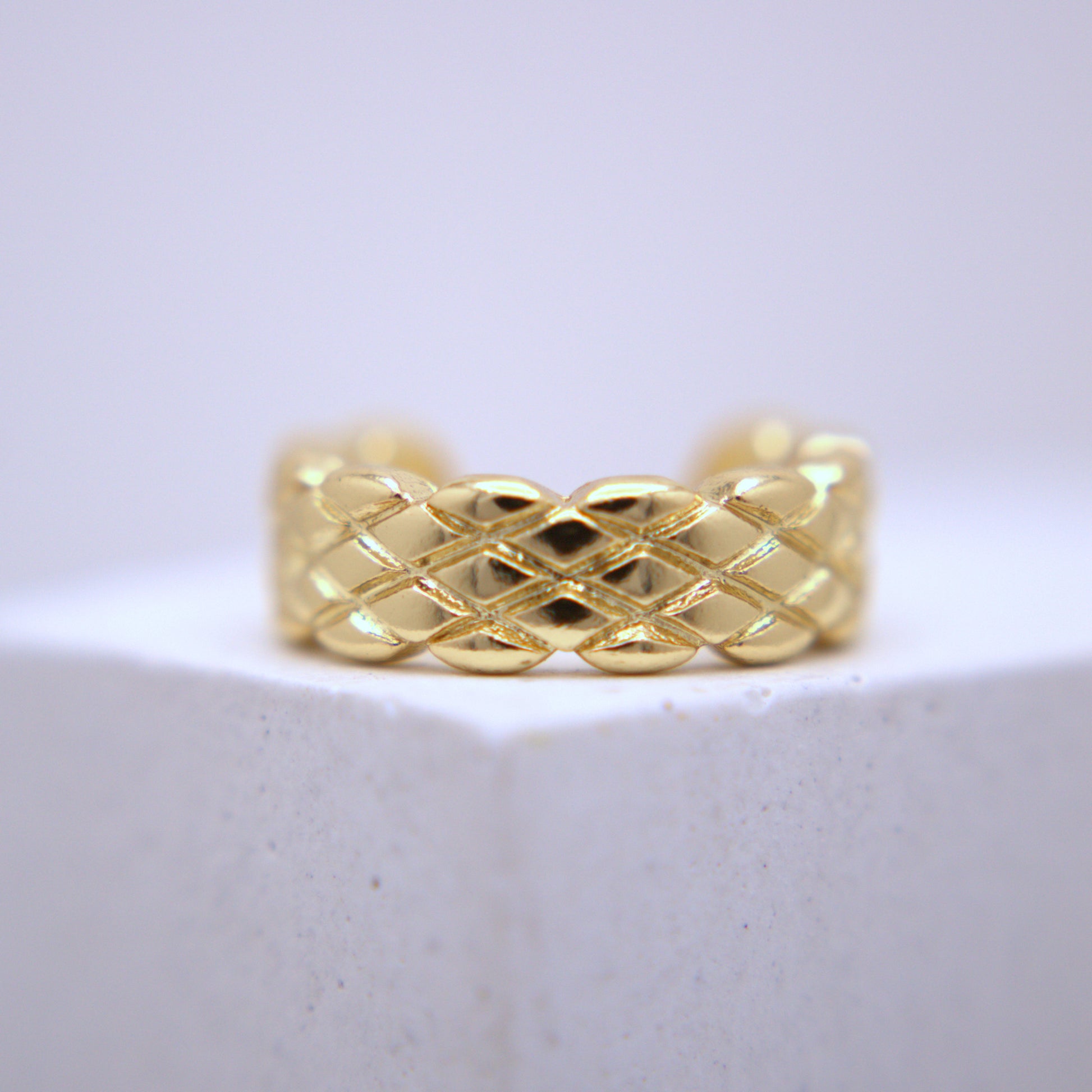 Gold woven ear cuff on a white background