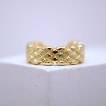 Gold woven ear cuff on a white background