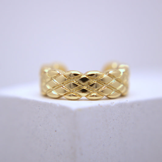 Gold woven ear cuff on a white background