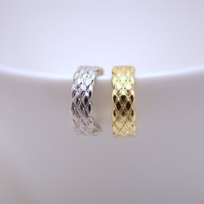 Two woven ear cuffs one silver and one gold, on a white background