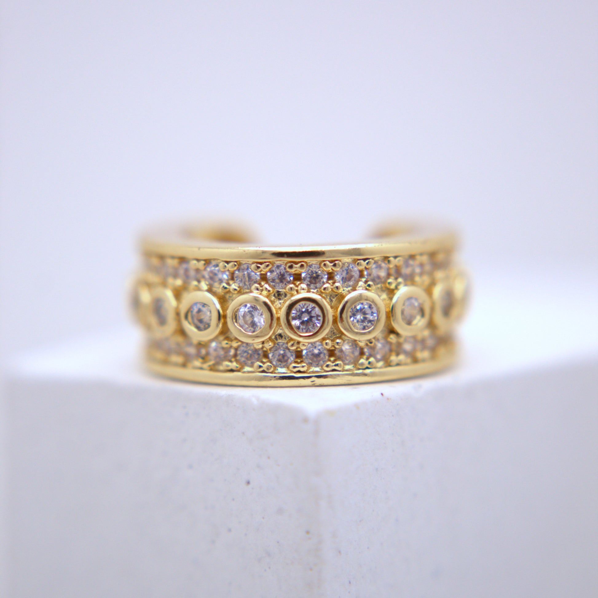 Gold ear cuff with diamond accents on a white surface