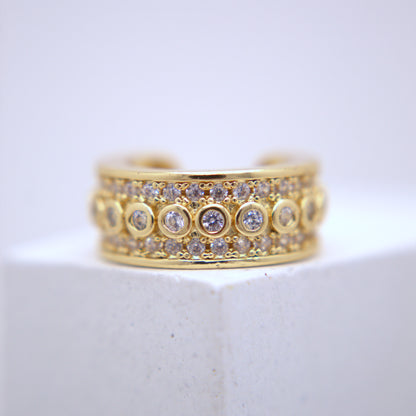 Gold ear cuff with diamond accents on a white surface