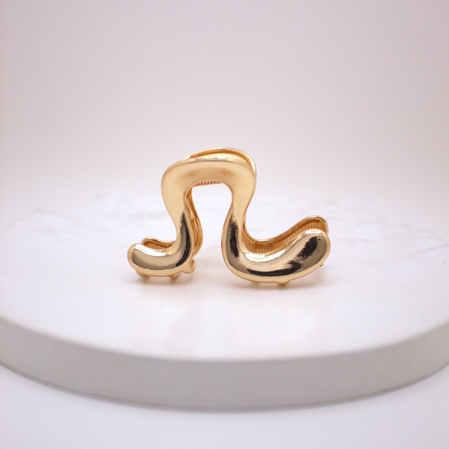 Gold hair clip on a white plate with a white background
