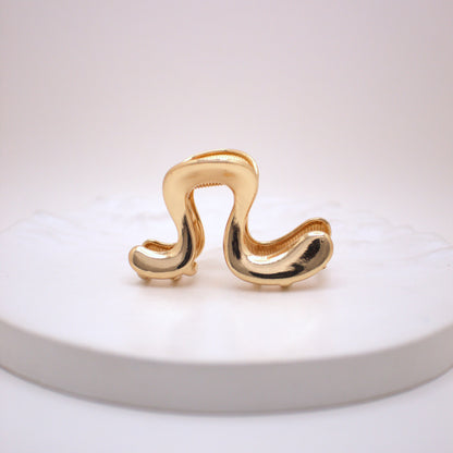 Gold hair clip on a white plate with a white background