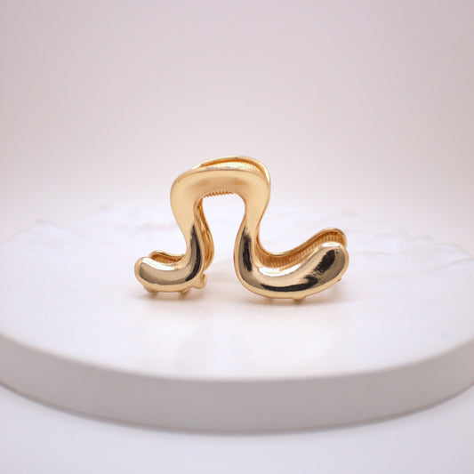 Gold hair clip on a white plate with a white background