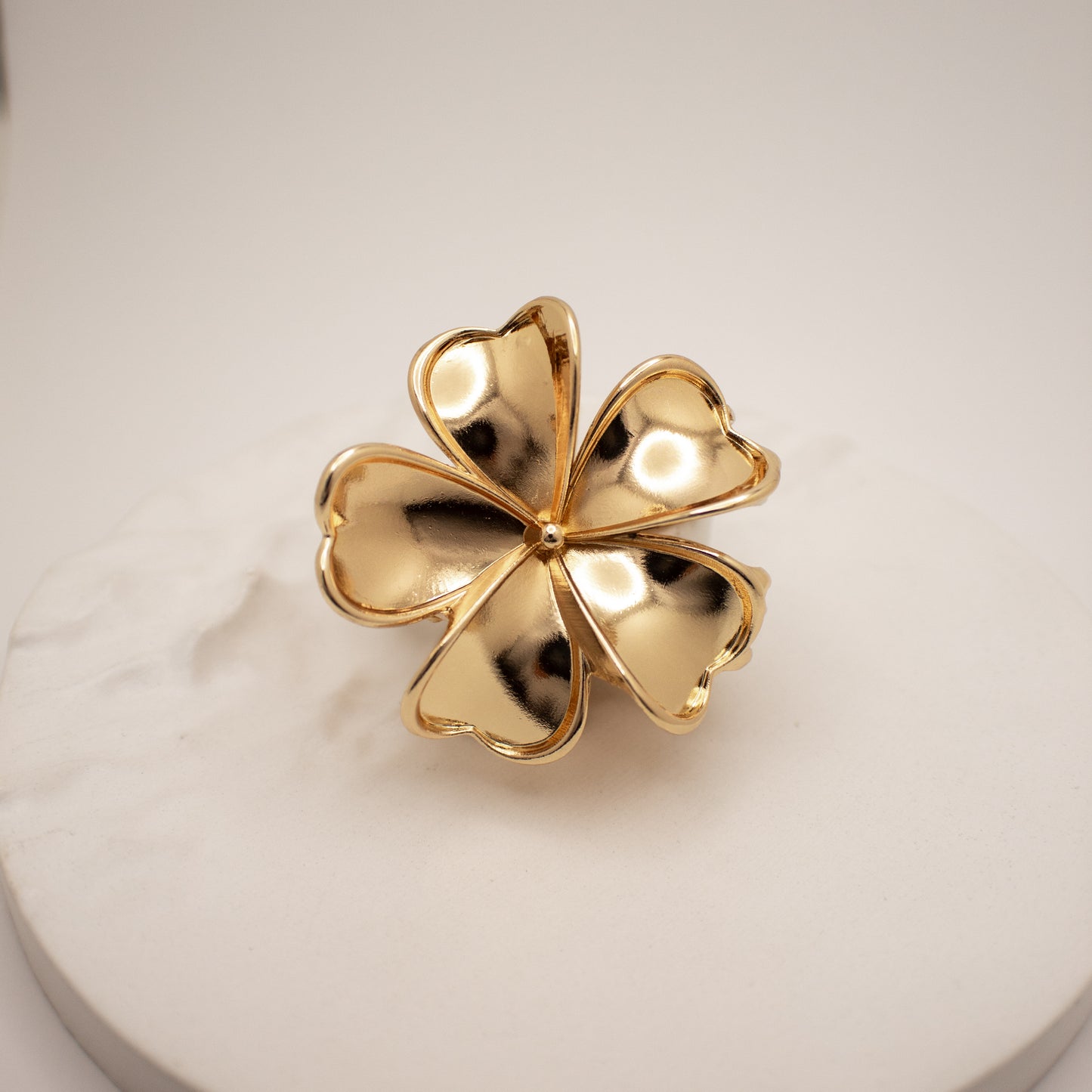 Gold four-leaf clover ring on a light background