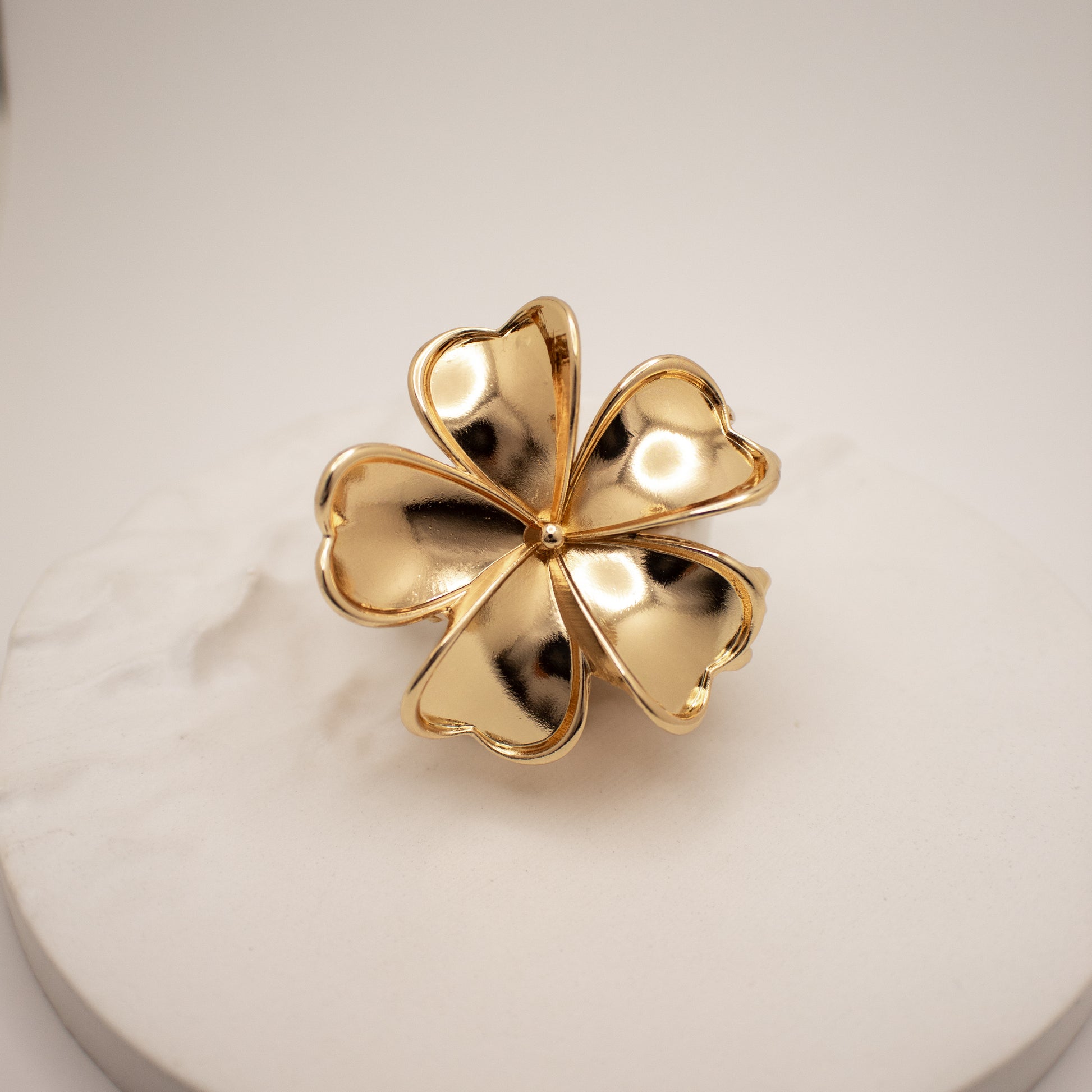 Gold four-leaf clover ring on a light background