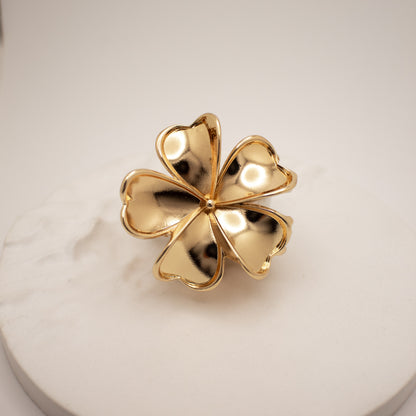 Gold four-leaf clover ring on a light background