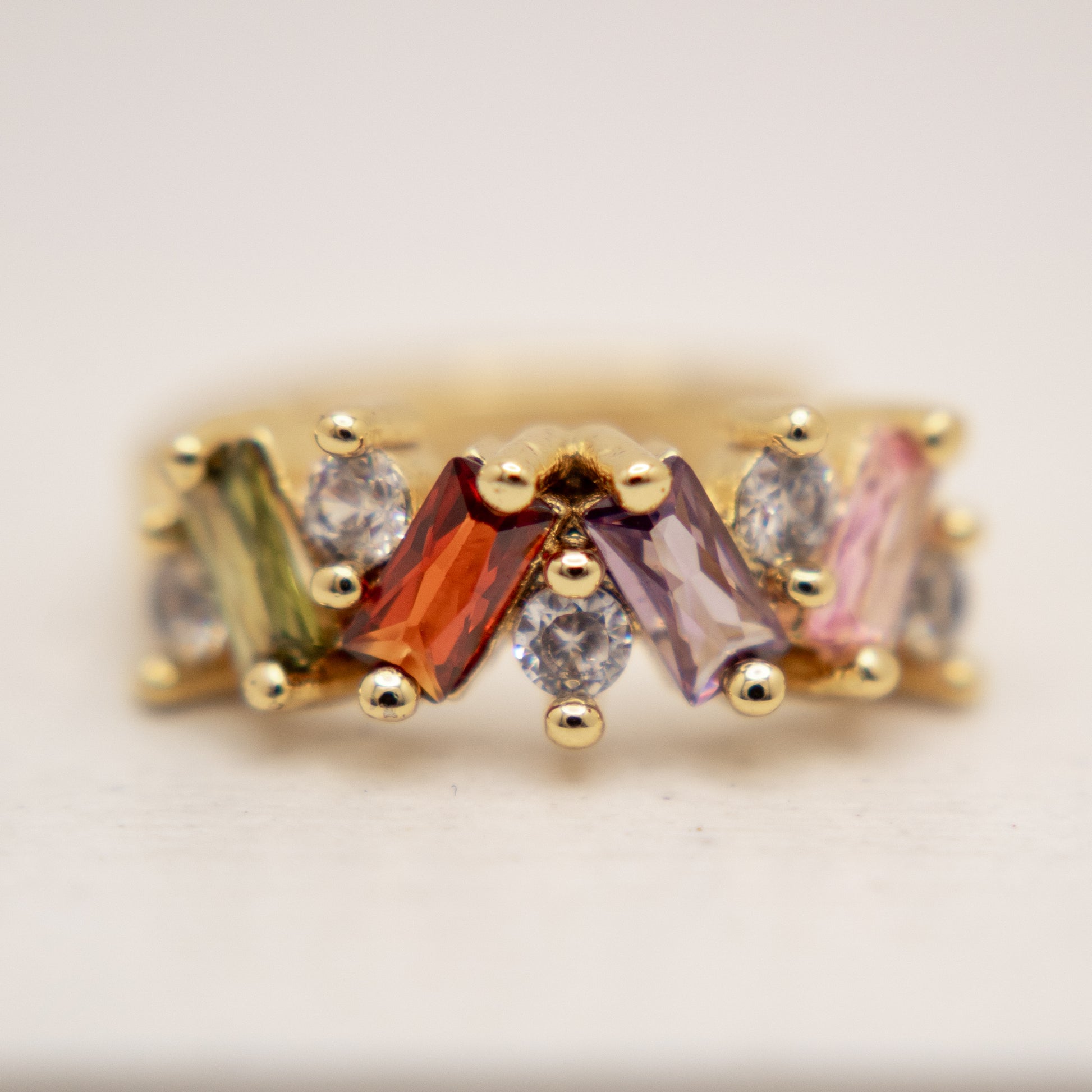 Gold ring with multicolored gemstones on a light background