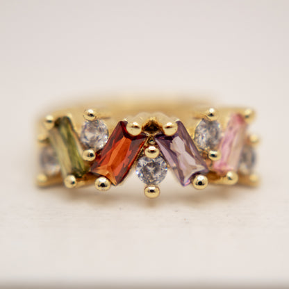 Gold ring with multicolored gemstones on a light background