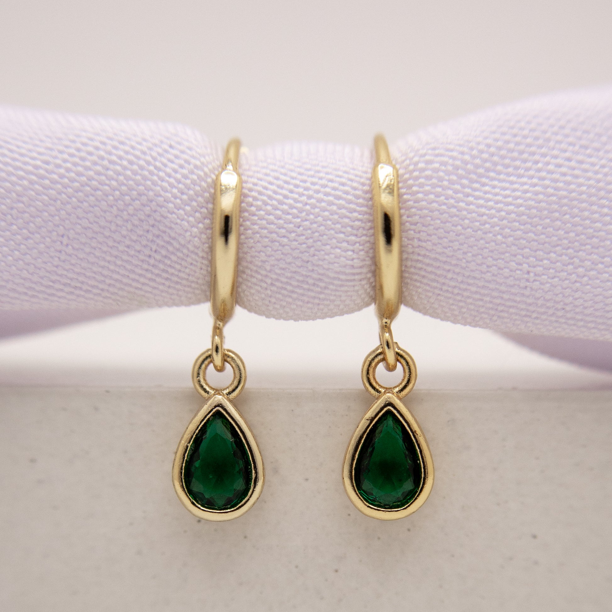 Gold earrings with green gemstones on a white background