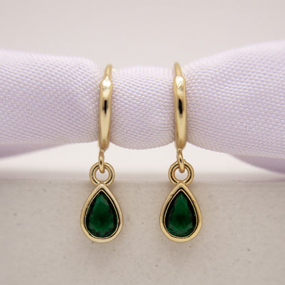 Gold earrings with green gemstones on a white background
