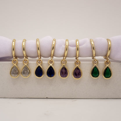 Gold teardrop earrings with colored stones on a white surface
