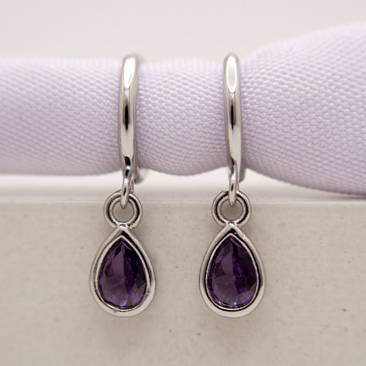 Silver earrings with purple teardrop stones on a white background