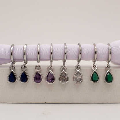 Set of teardrop-shaped jewelry charms with different colored stones on a white background