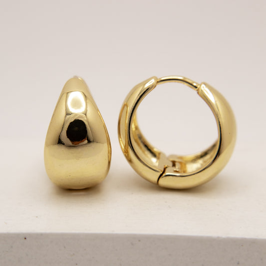 Gold hoop earrings on a light gray background