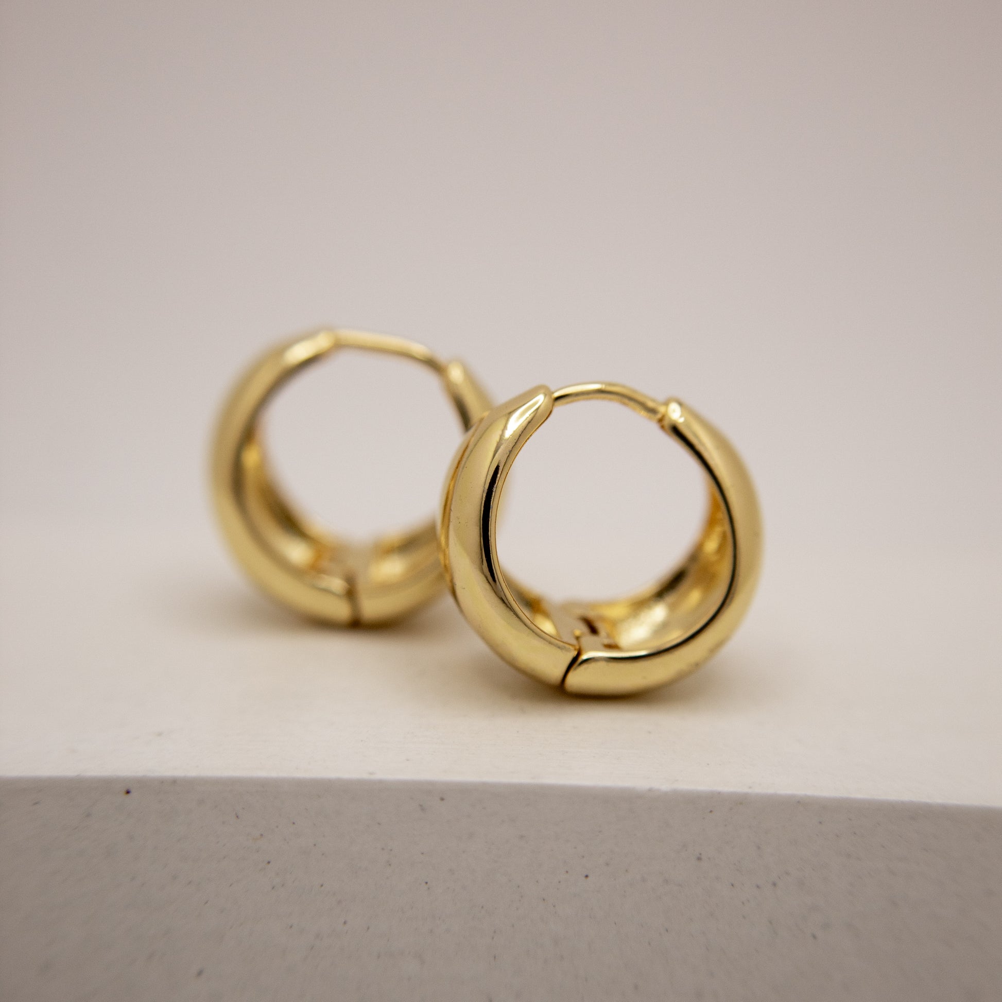 Gold hoop earrings on a light gray background