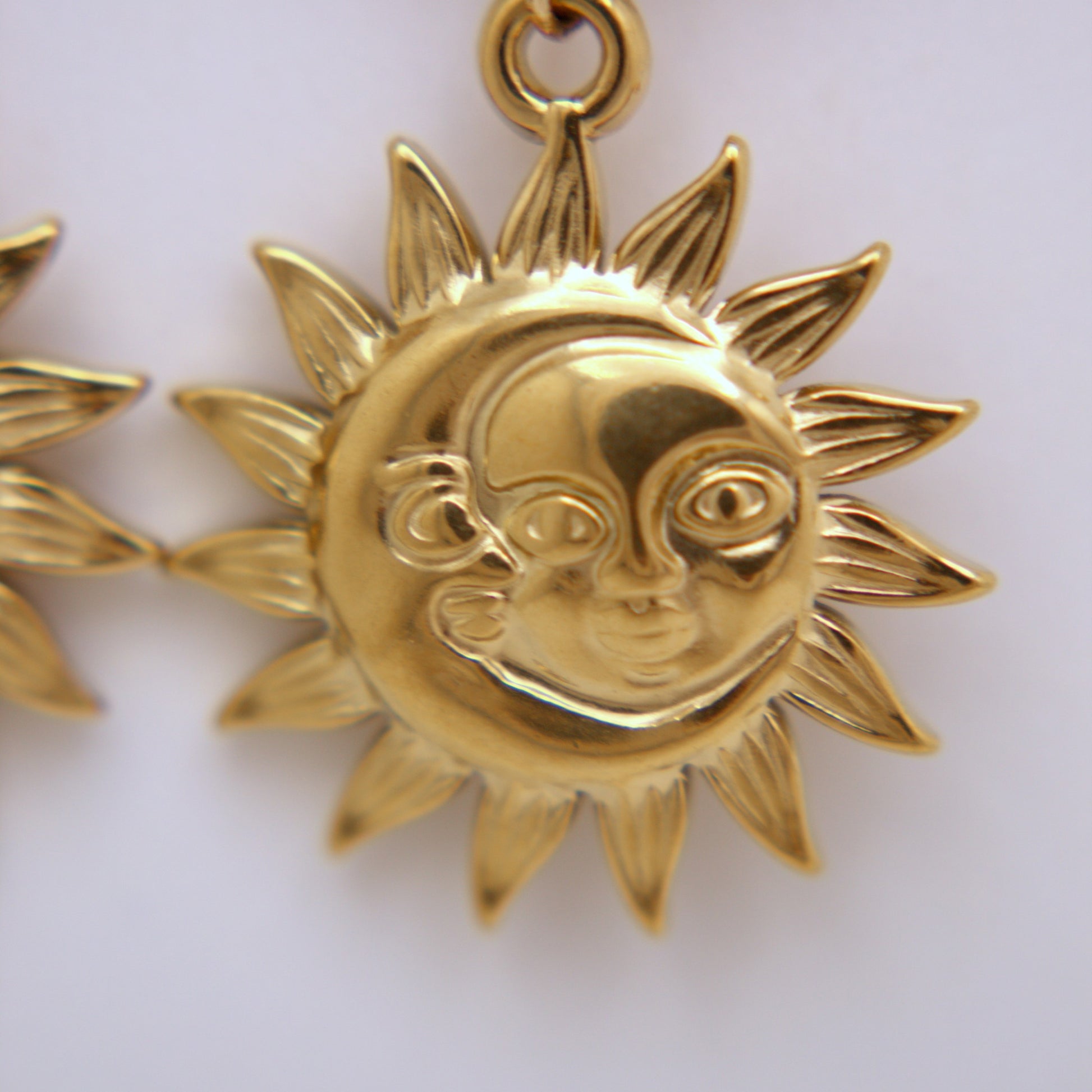 Gold sun and moon pendant on a white background