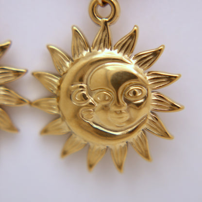 Gold sun and moon pendant on a white background