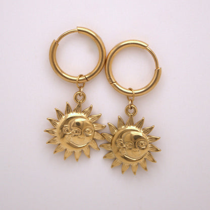 Gold hoop earrings with sun-shaped charms on a white background