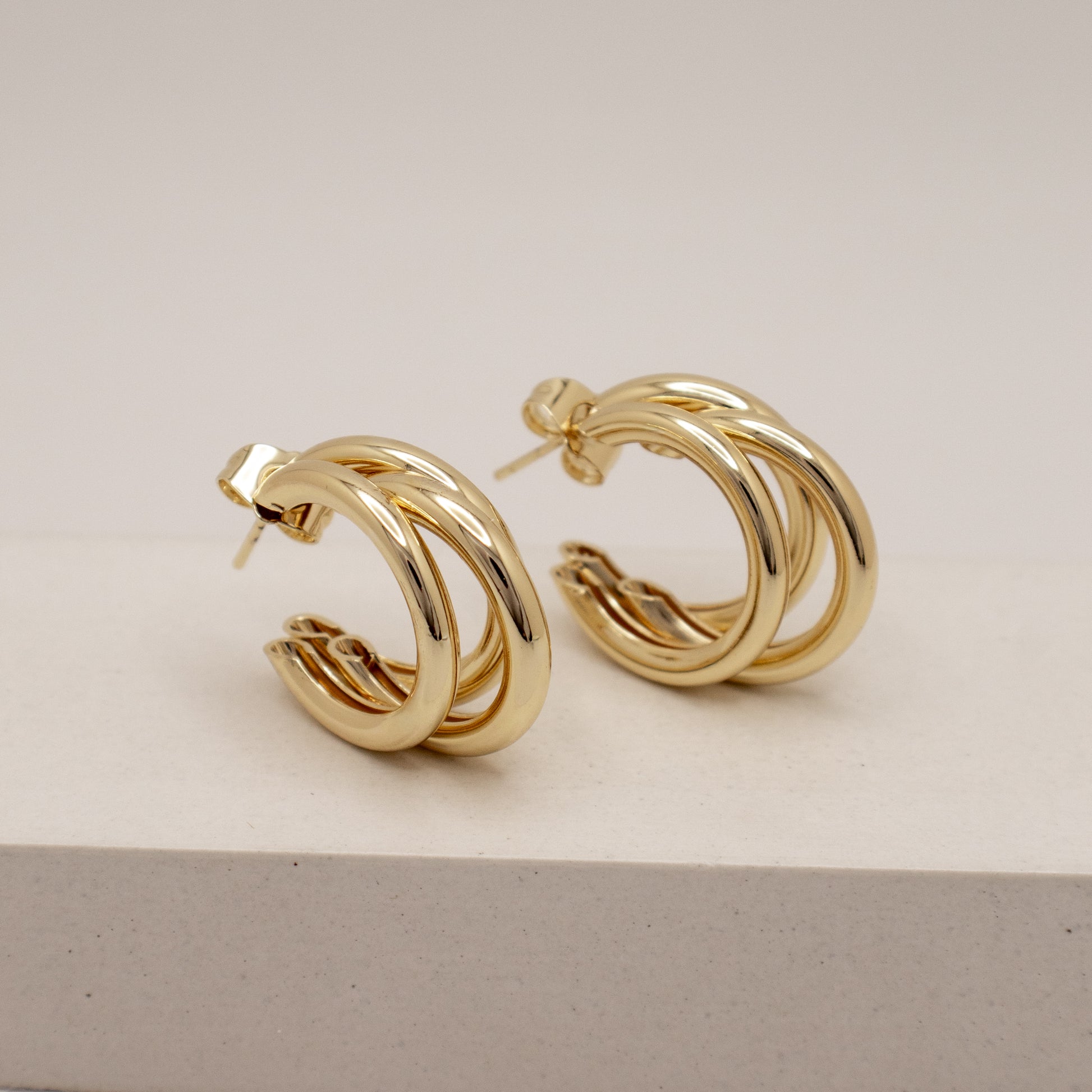 Gold hoop earrings on a light beige background