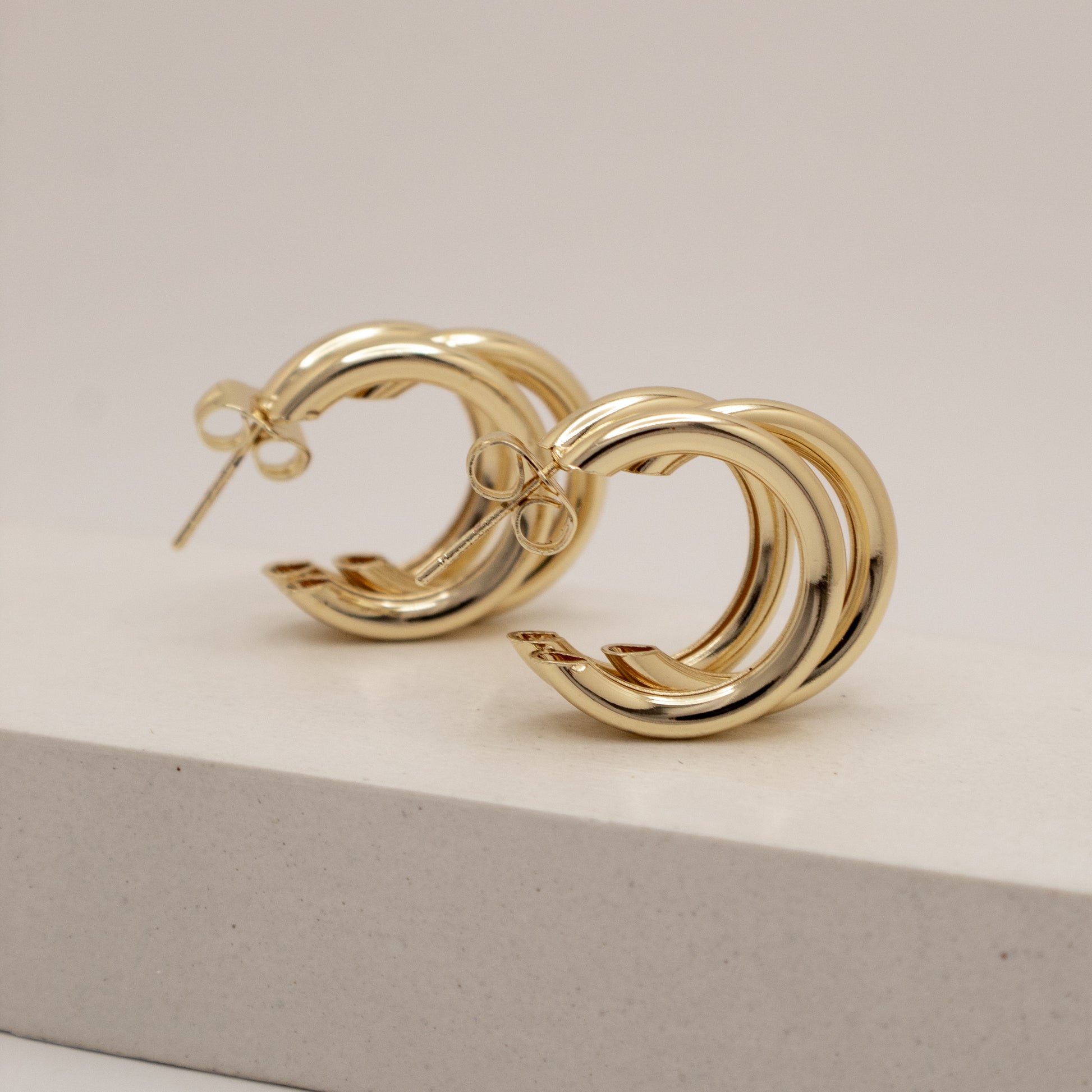Gold hoop earrings on a light beige background