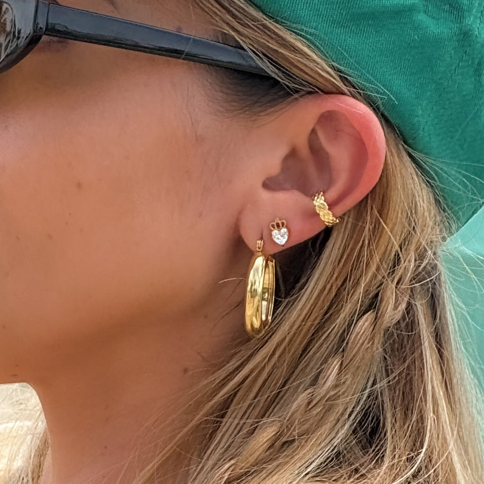 Close-up of a person wearing gold hoop earrings with a teal headband.