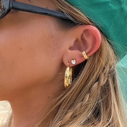 Close-up of a person wearing gold hoop earrings with a teal headband.