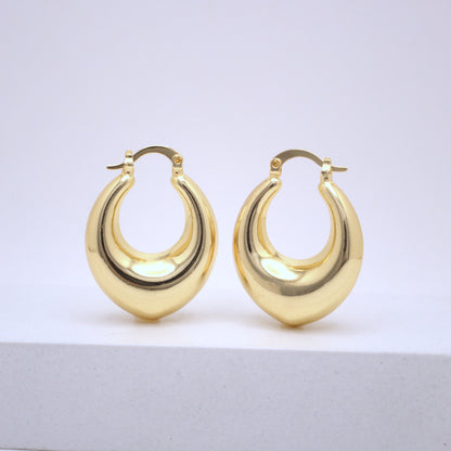 Pair of gold hoop earrings on a light gray surface with a white background