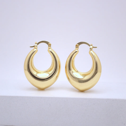 Pair of gold hoop earrings on a light gray surface with a white background