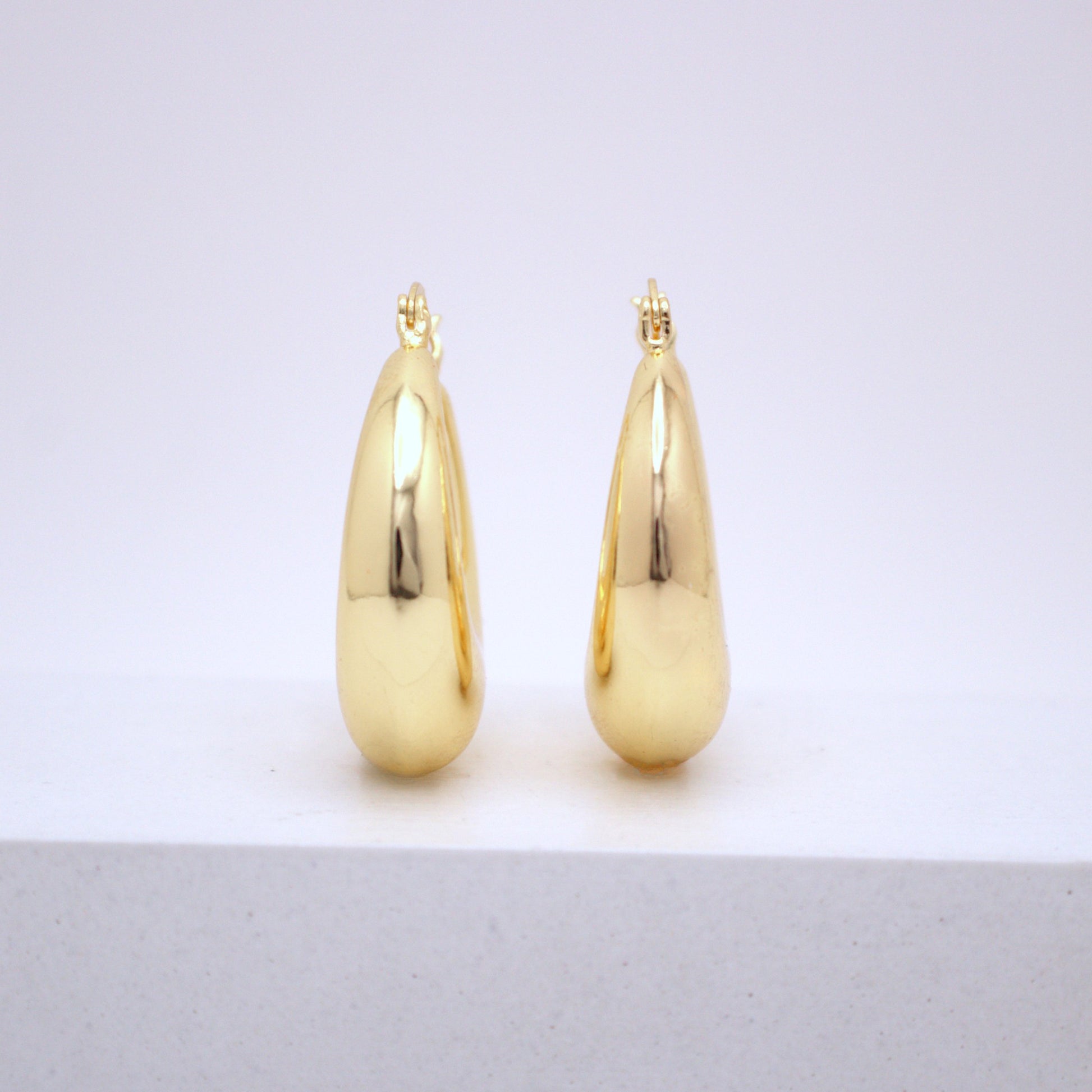 Pair of gold teardrop earrings on a white background
