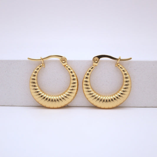 Gold hoop earrings on a white surface